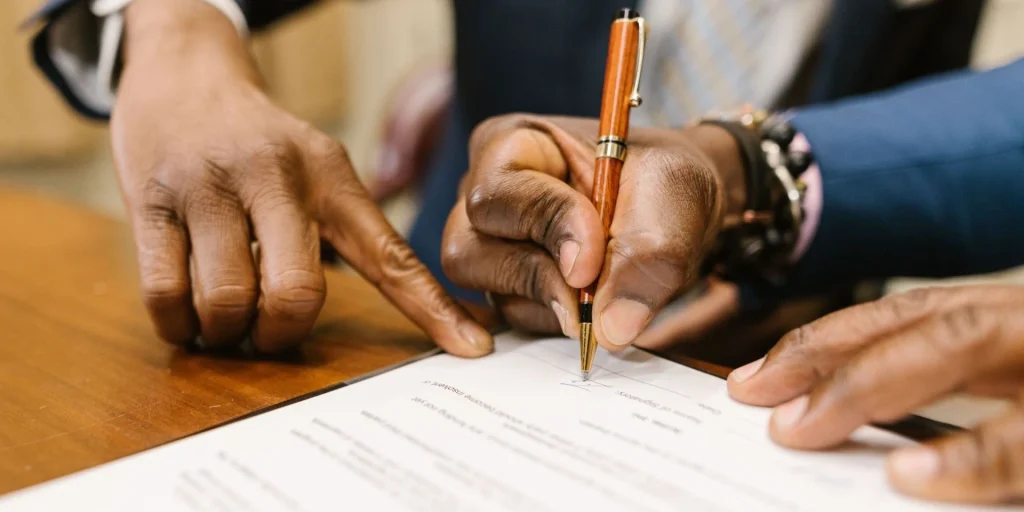 Close-up of professionals signing an end of service contract at an office desk