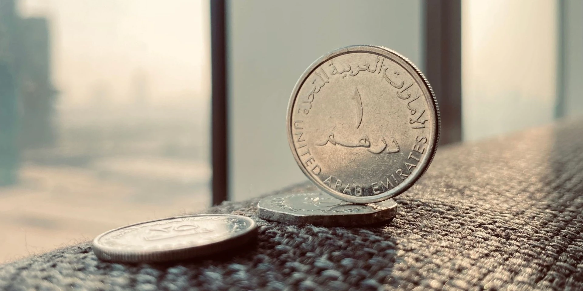 UAE dirham coins with the Dubai skyline in the background